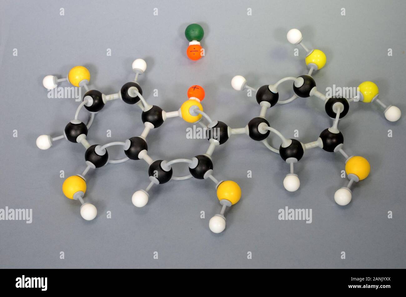 Molecule model of Paraffin. White is Hydrogen, black is Carbon, yellow is Oxygen and green is Chlorine. The orange spheres represent charges in a coor Stock Photo
