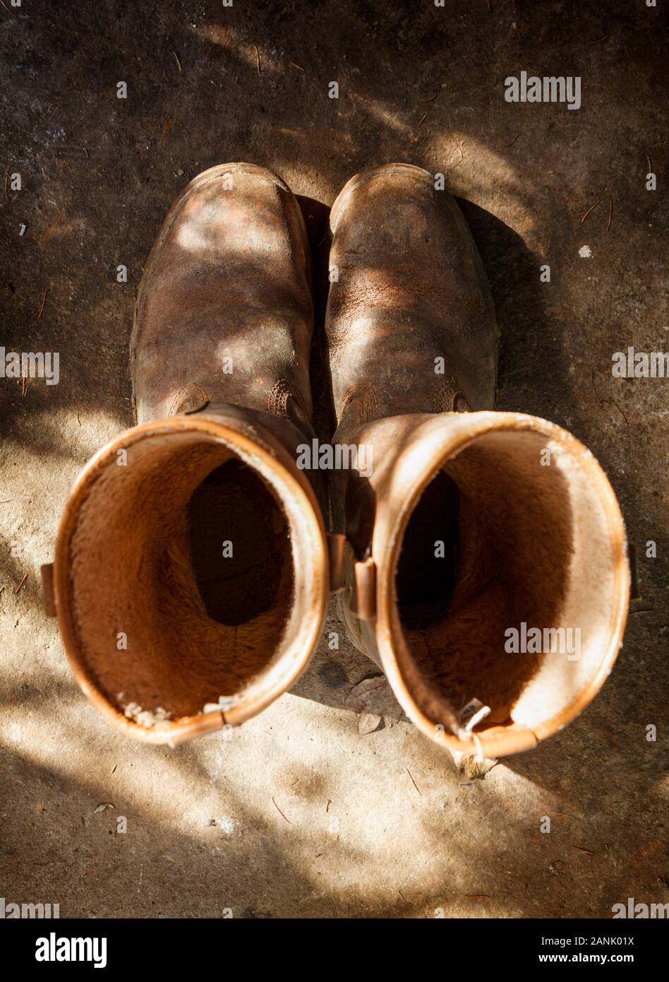 Old and used brown work boots, shot from above on a dirty shed floor Stock Photo