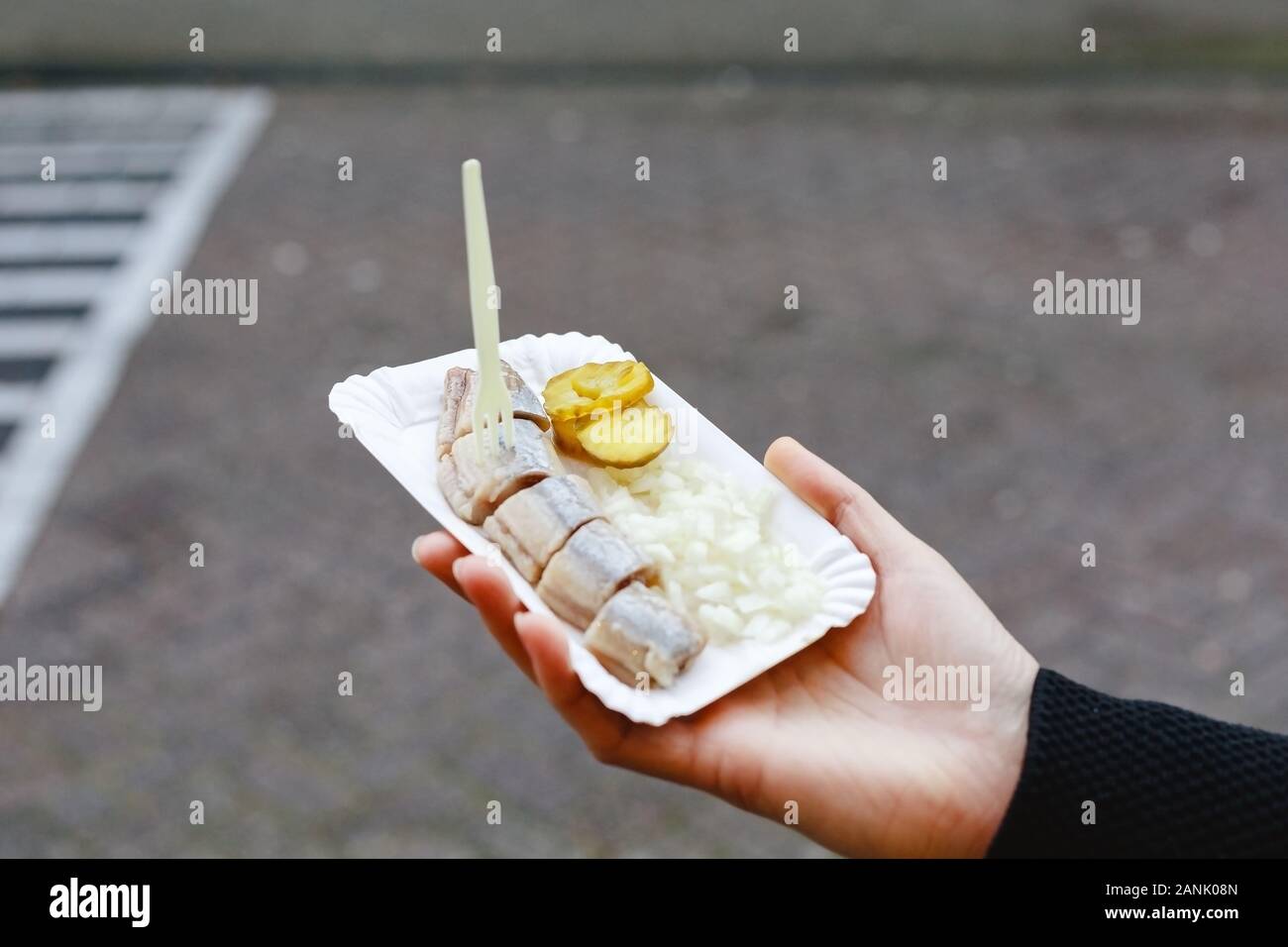 Holland herring fish in female hand outside. Traditional Dutch street