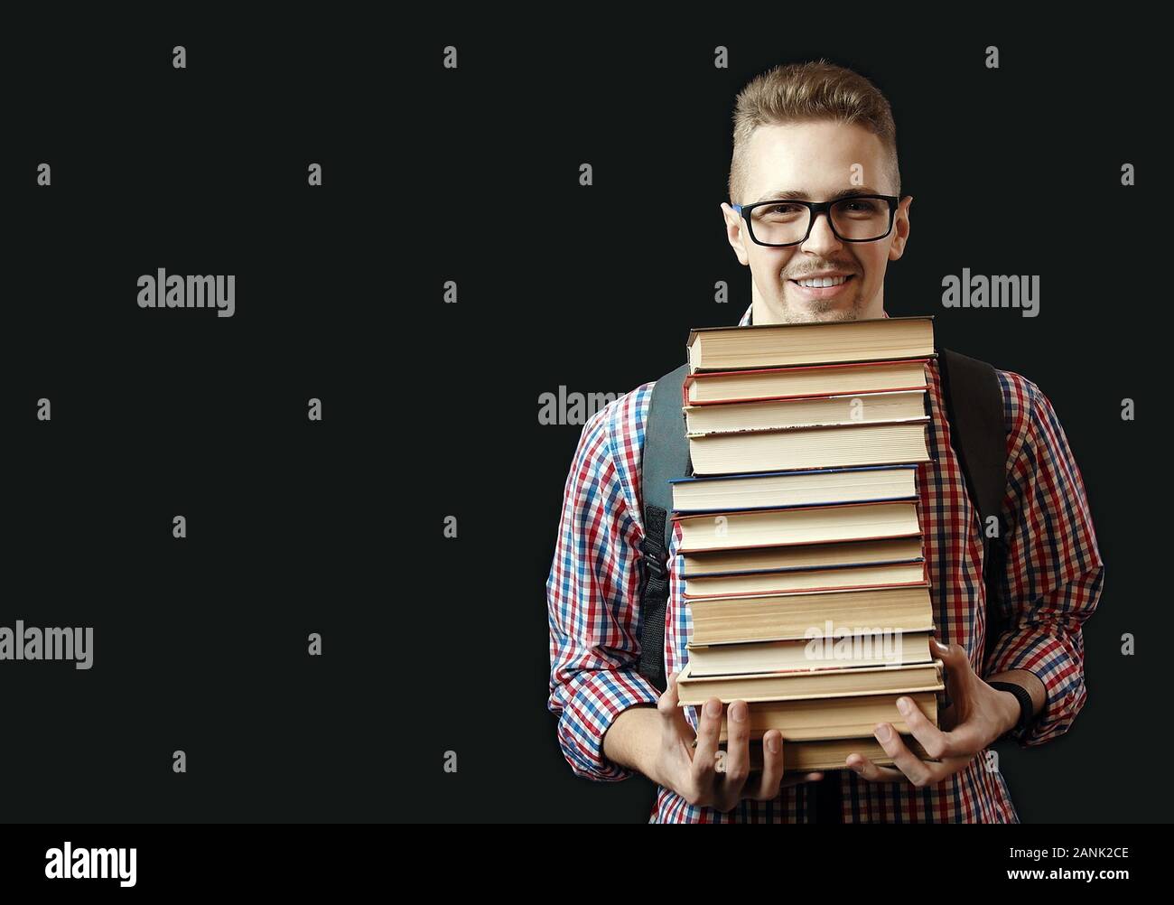 Front view of smiling student with glasses and backpack carrying many ...