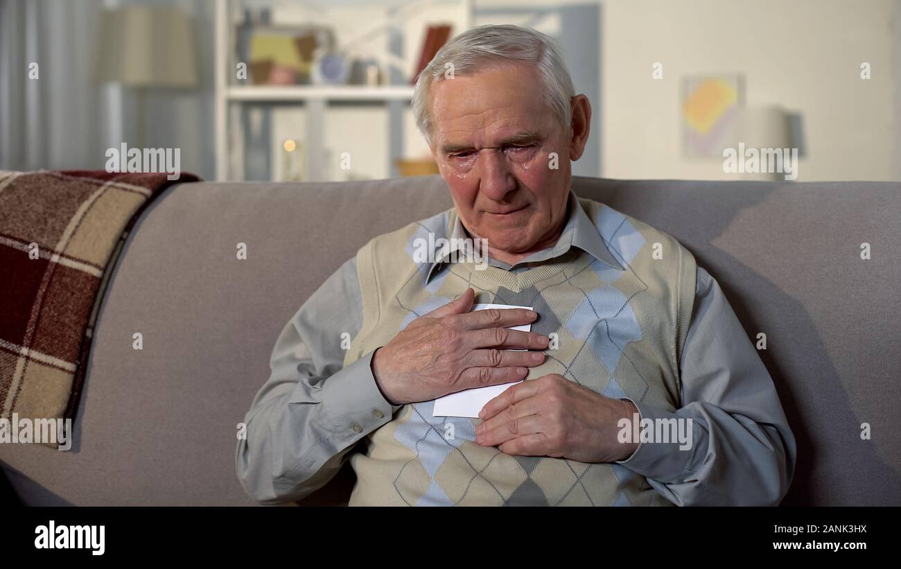 Sad old male with tears on face hugging wife photo missing family, loneliness Stock Photo