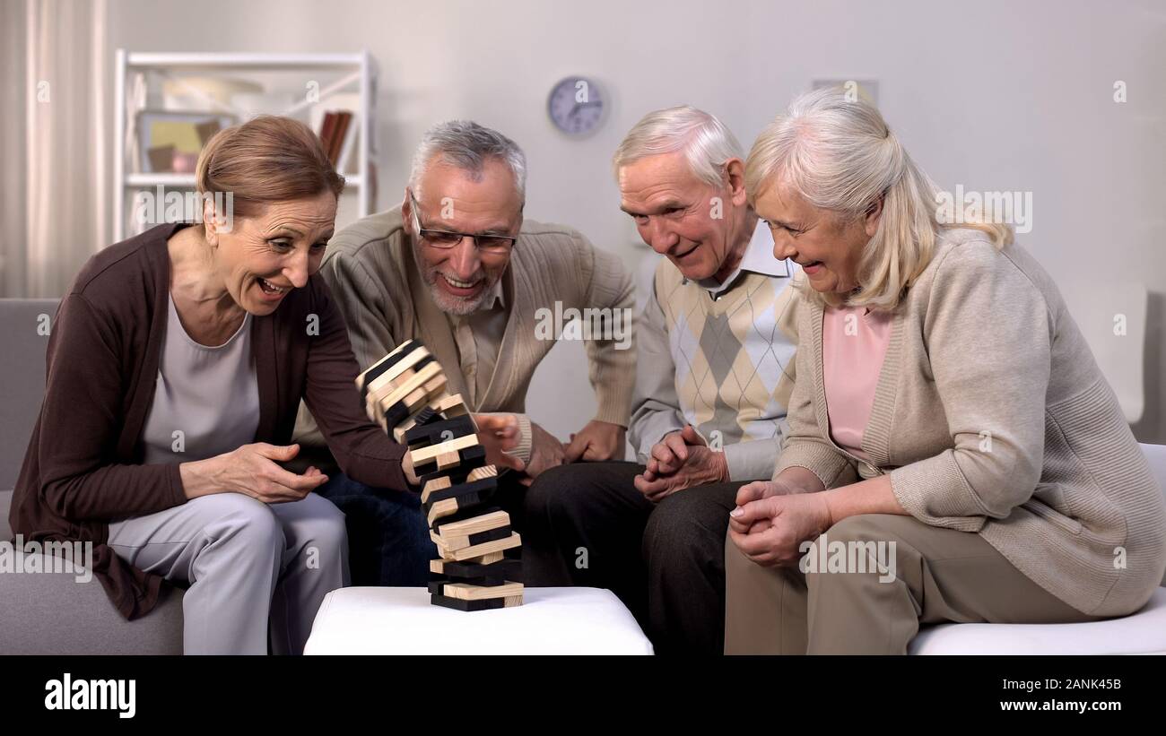 Happy mature people playing board game together nursing home, pension free time Stock Photo