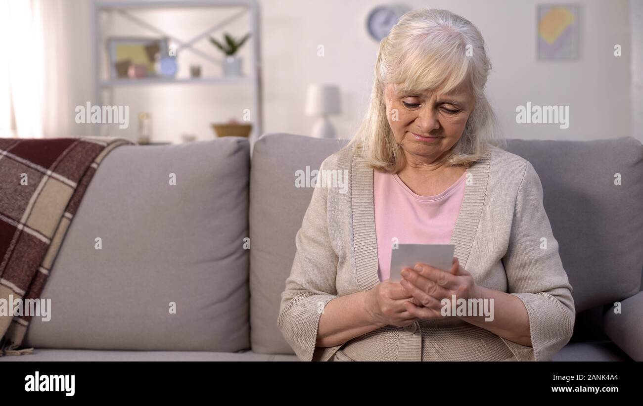 Lonely retired woman looking at photo in hands, separation hopelessness, sadness Stock Photo