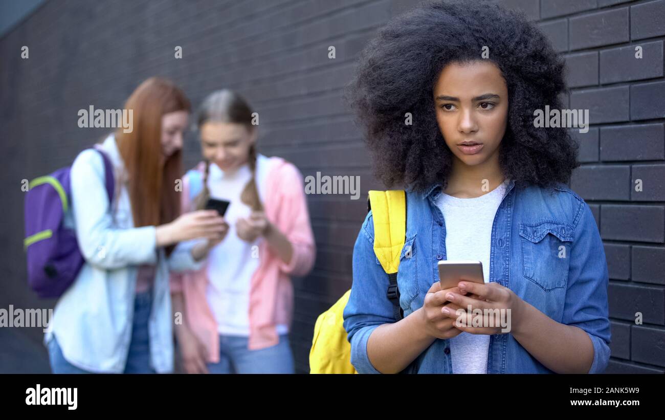 Sad african schoolgirl reading humiliating message, cyber bullying embarrassment Stock Photo