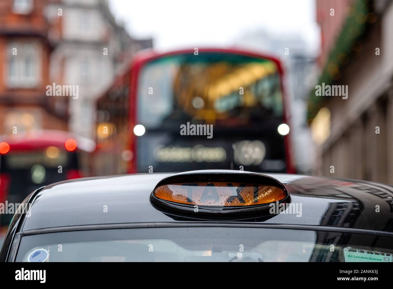 London, England, UK - December 31, 2019: A british london black taxi cab sign with defocused red bus in background - image Stock Photo