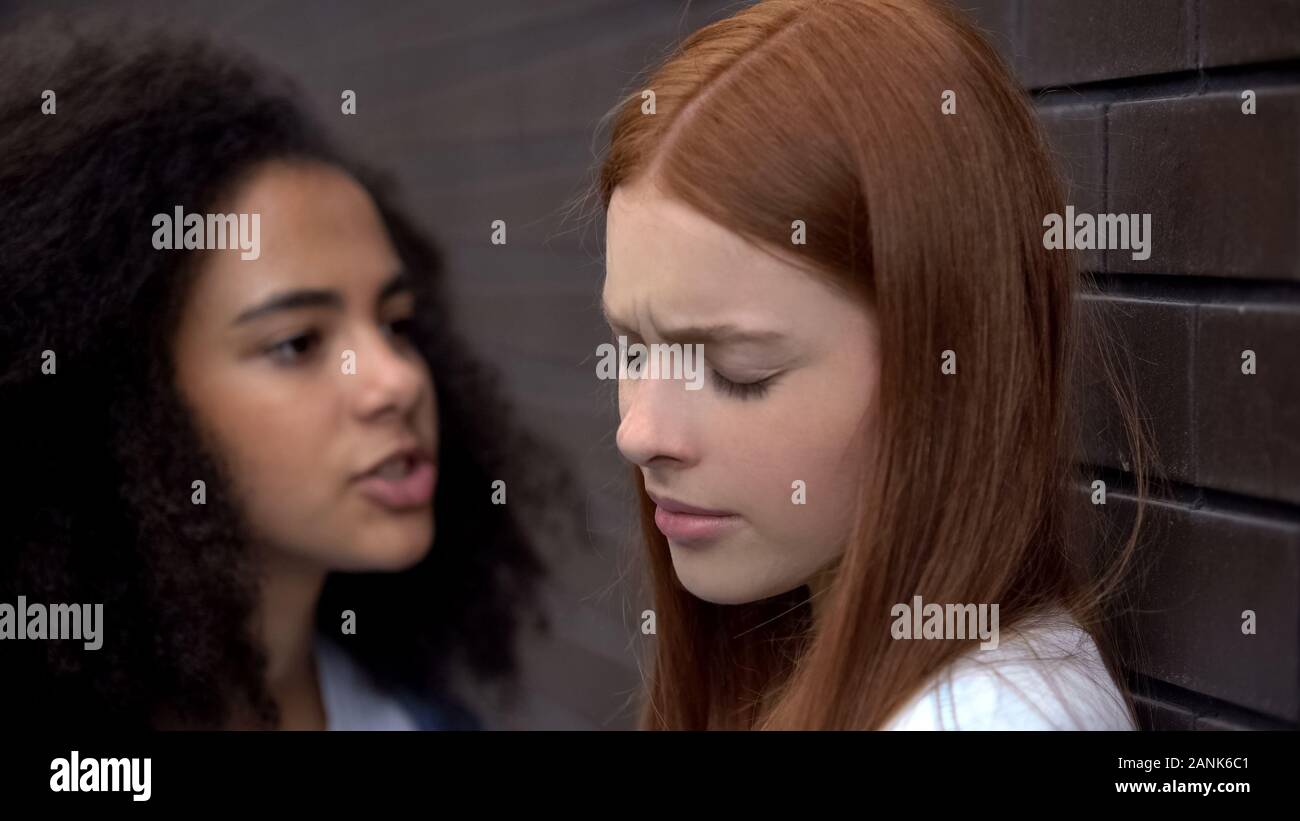 Black high school student threatening red-haired teenager in backyard, bullying Stock Photo