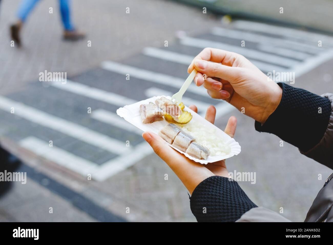 Holland herring fish in female hand outside. Traditional Dutch street