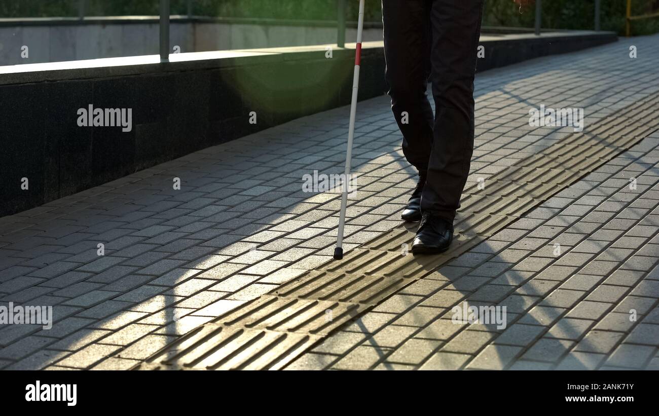 Blind man walk along tactile paving, safe urban navigation for visually impaired Stock Photo