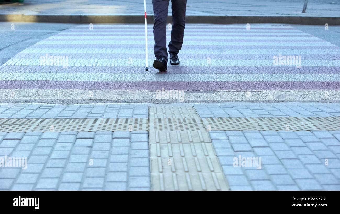 Blind male crossing street with white cane, traffic laws of road crossing Stock Photo