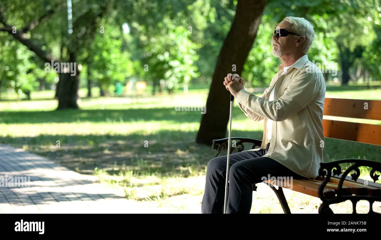 Old blind man sitting on bench, thinking about life injustice feeling frustrated Stock Photo