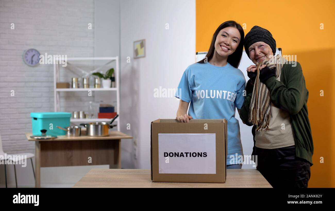 Happy refugee and volunteer smiling camera, receiving clothes homeless center Stock Photo