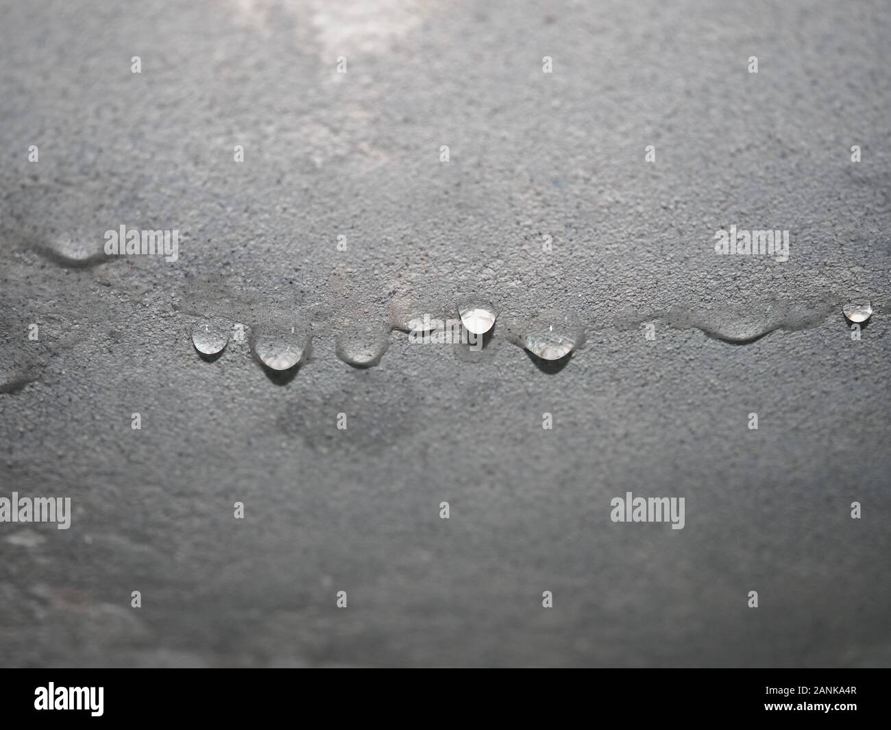 damage caused by dampness and moisture on a ceiling, with droplets of water infiltration Stock Photo