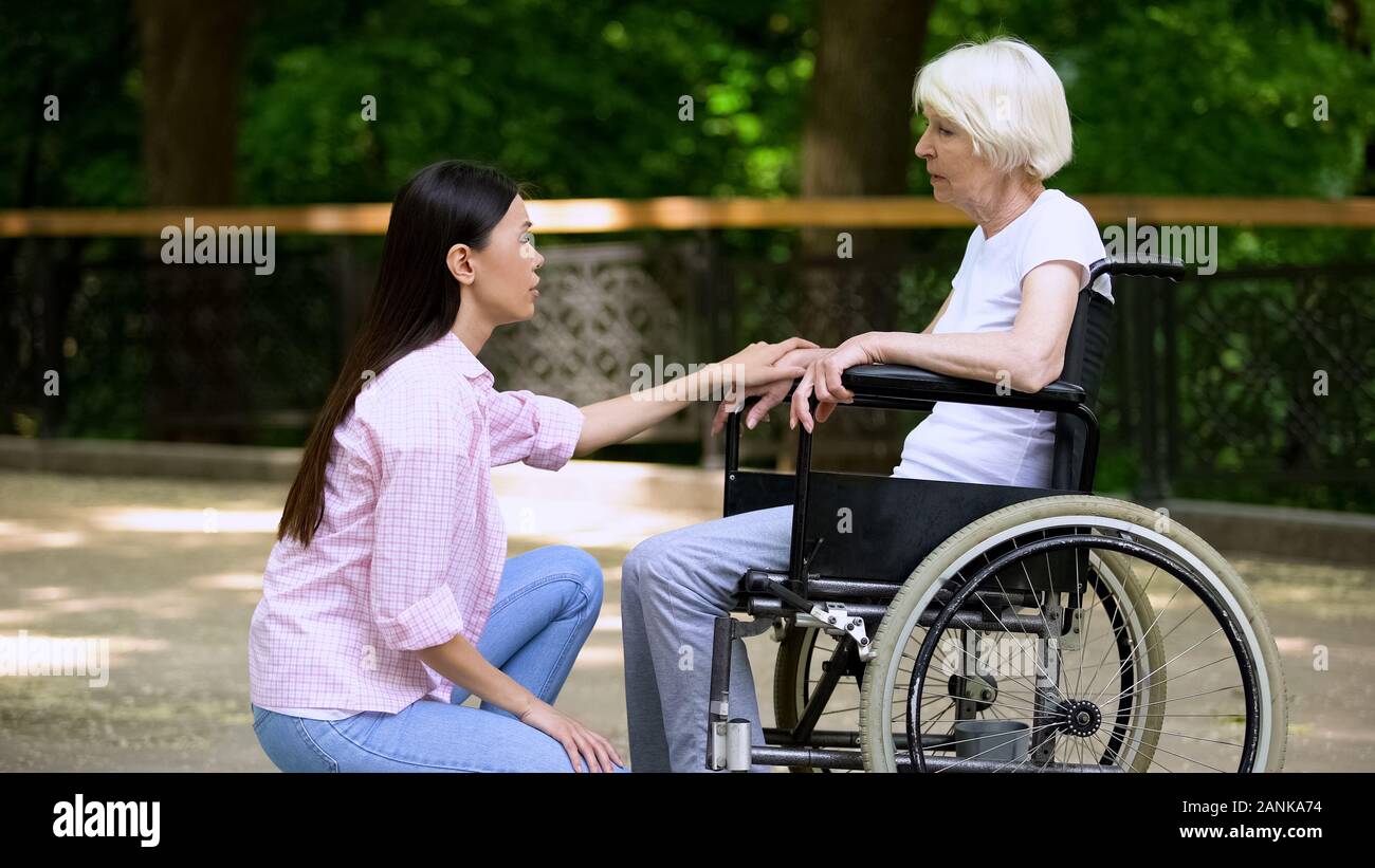 Volunteer talking with crying woman in wheelchair, psychological ...