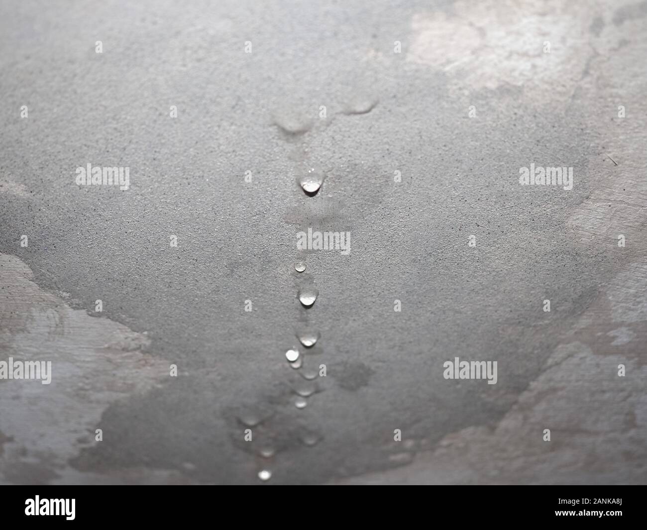 damage caused by dampness and moisture on a ceiling, with droplets of water infiltration Stock Photo