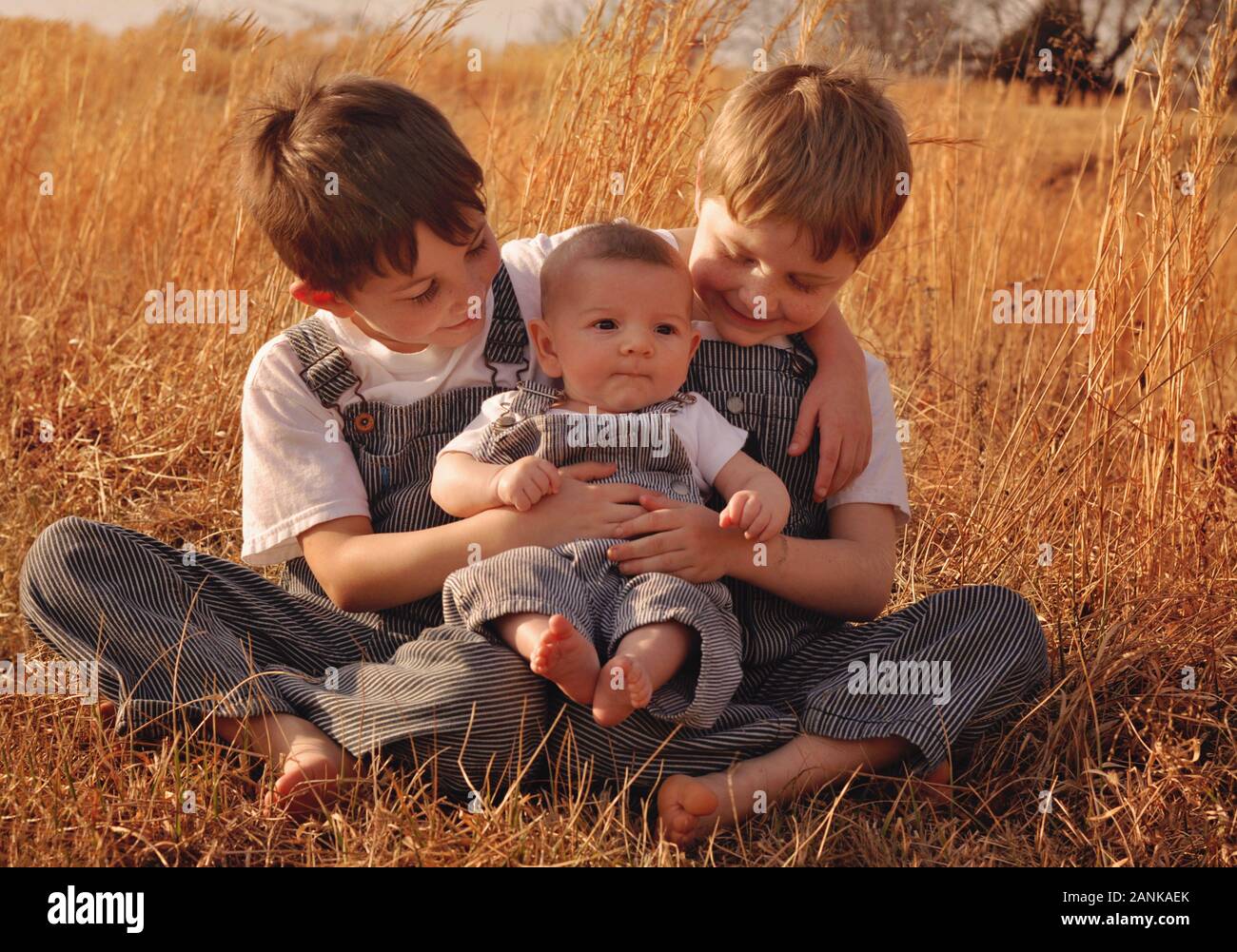 Three boy brothers wearing matching striped overalls Stock Photo