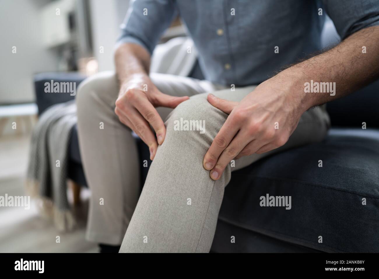 Man Suffering From Knee Pain Sitting On Sofa Stock Photo Alamy