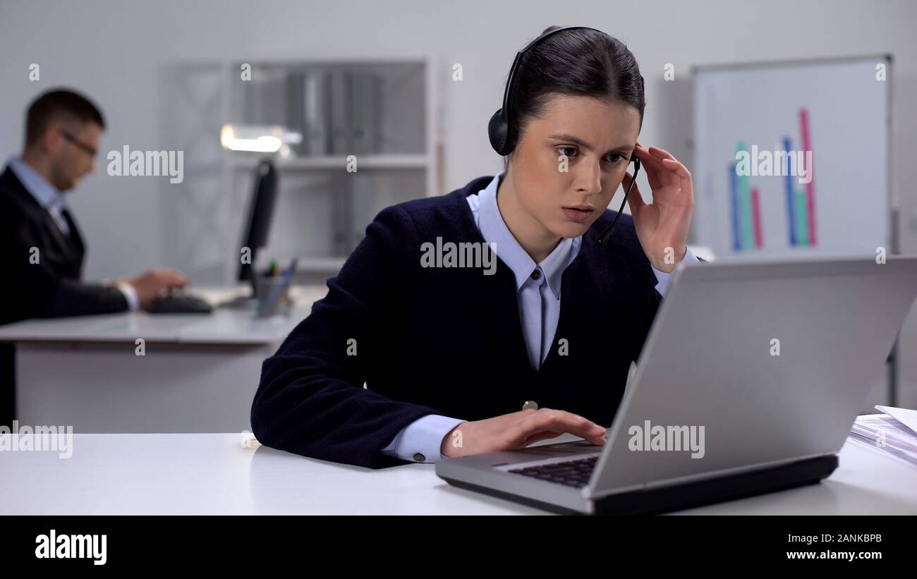 Call center manager in headset checking data on laptop, customer support Stock Photo