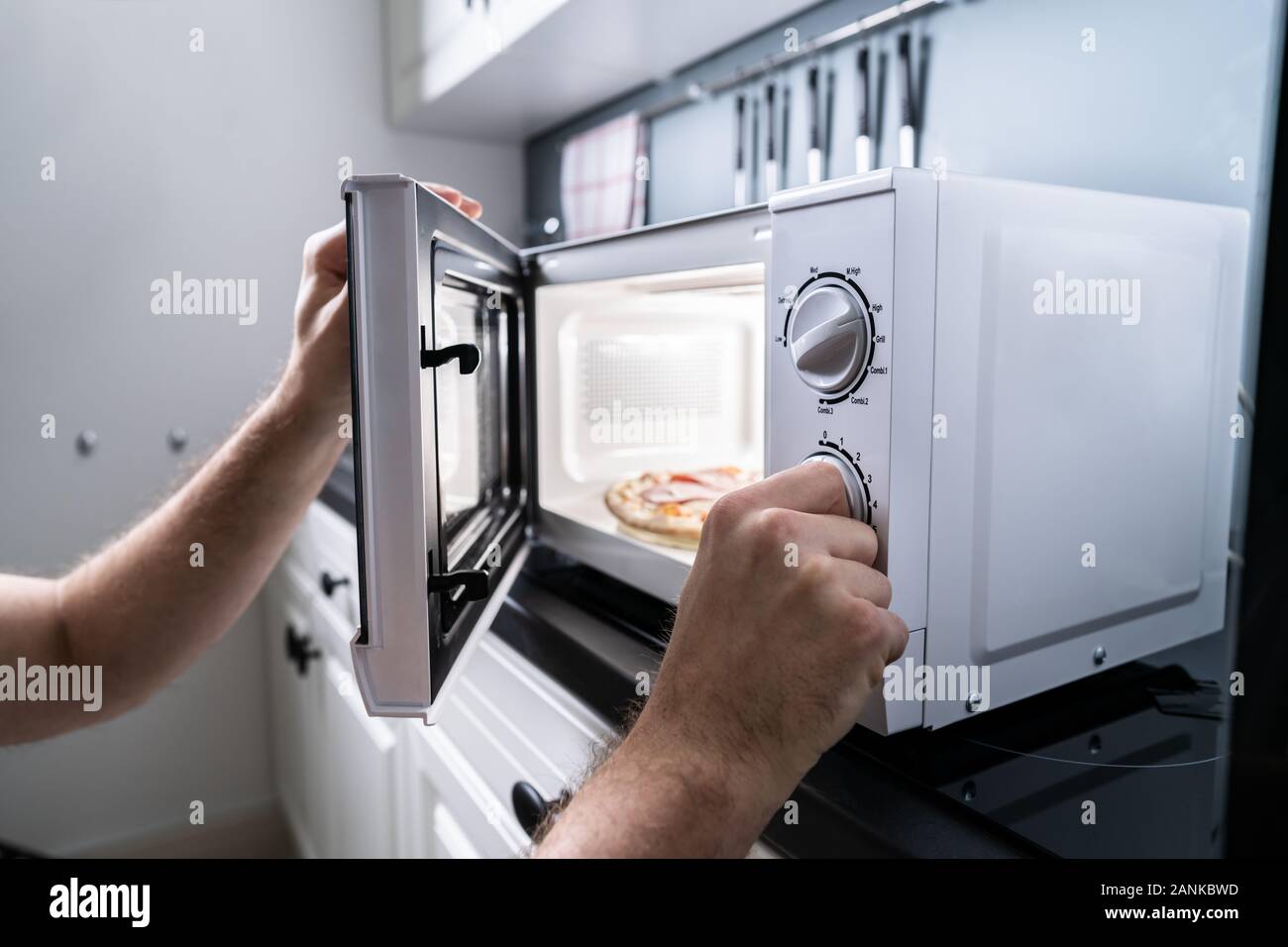 Human Hand Baking Pizza In Microwave Oven Stock Photo
