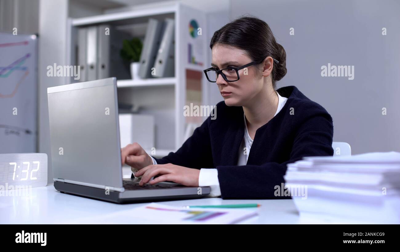 Female office worker typing on computer, looking responsible and focused on task Stock Photo