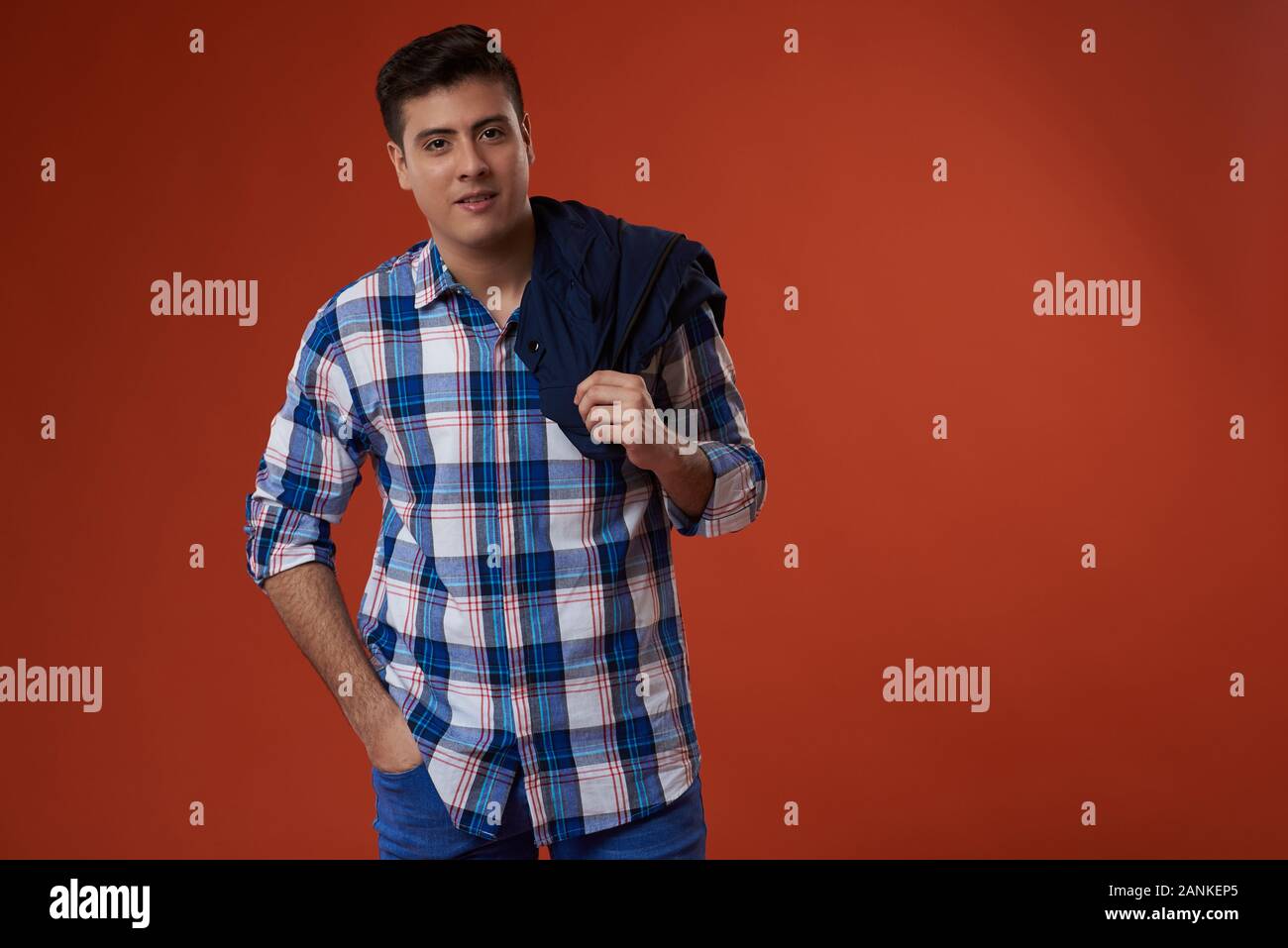 Young man with jacket on shoulder isolated on orange color studio background Stock Photo