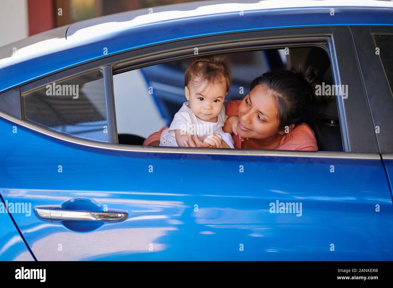 Young mom with baby girl in car open window Stock Photo
