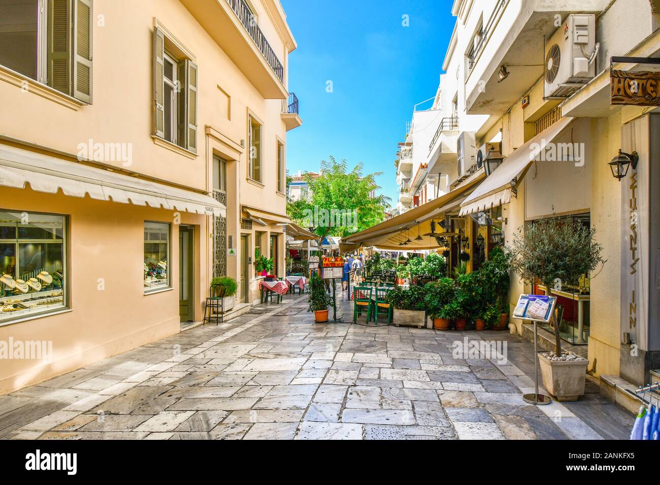 A picturesque sidewalk cafe on a narrow pedestrian street through the tourist district of Plaka in the historic center of Athens, Greece. Stock Photo