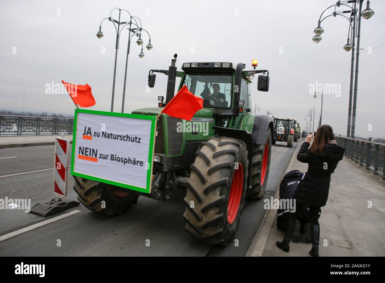 Mainz, Germany. 17th January 2020. Tractors cross the Theodor-Heuss-Bridge from Hesse into Mainz. A poster that reads “Yes to conservation - No to biosphere” hangs on the front of a tractor. Over 800 farmers with their tractor protested outside the ZDF TV station in Mainz against the media reporting of the agricultural politics. Afterwards they try to create the world wide longest mobile tractor chain by driving from the TV station through Rhenish Hesse, to protest against the new fertiliser regulations. Stock Photo