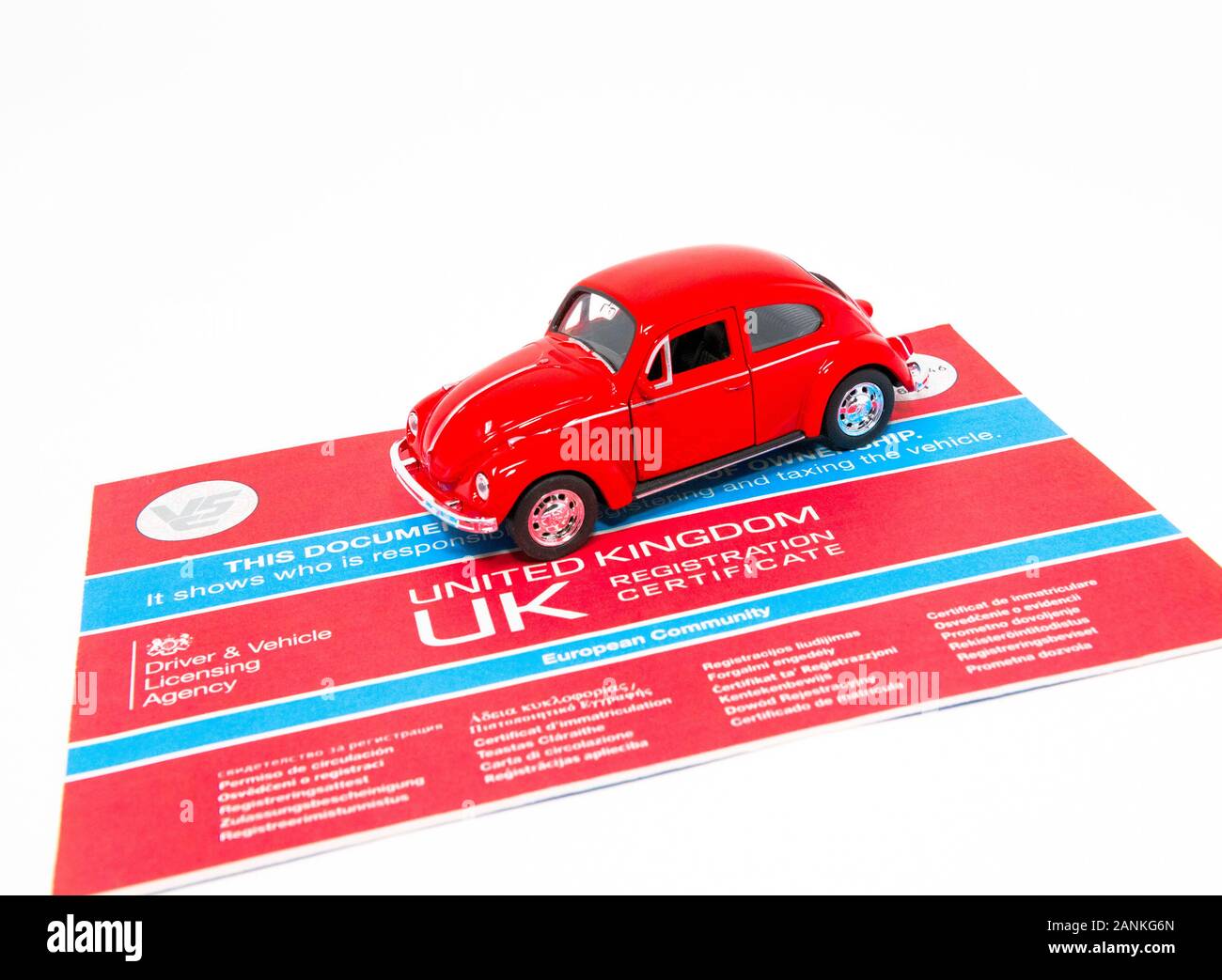 Red Volkswagen Beetle toy with a V5C document. Stock Photo