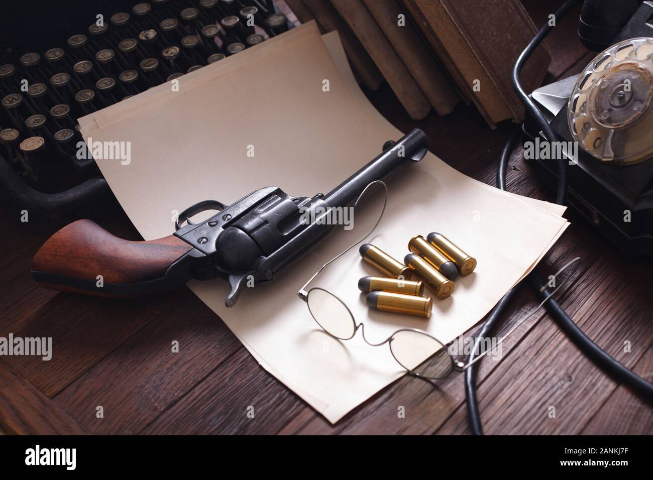 Old retro vintage typewriter with revolver and blank sheet of paper on wooden table Stock Photo