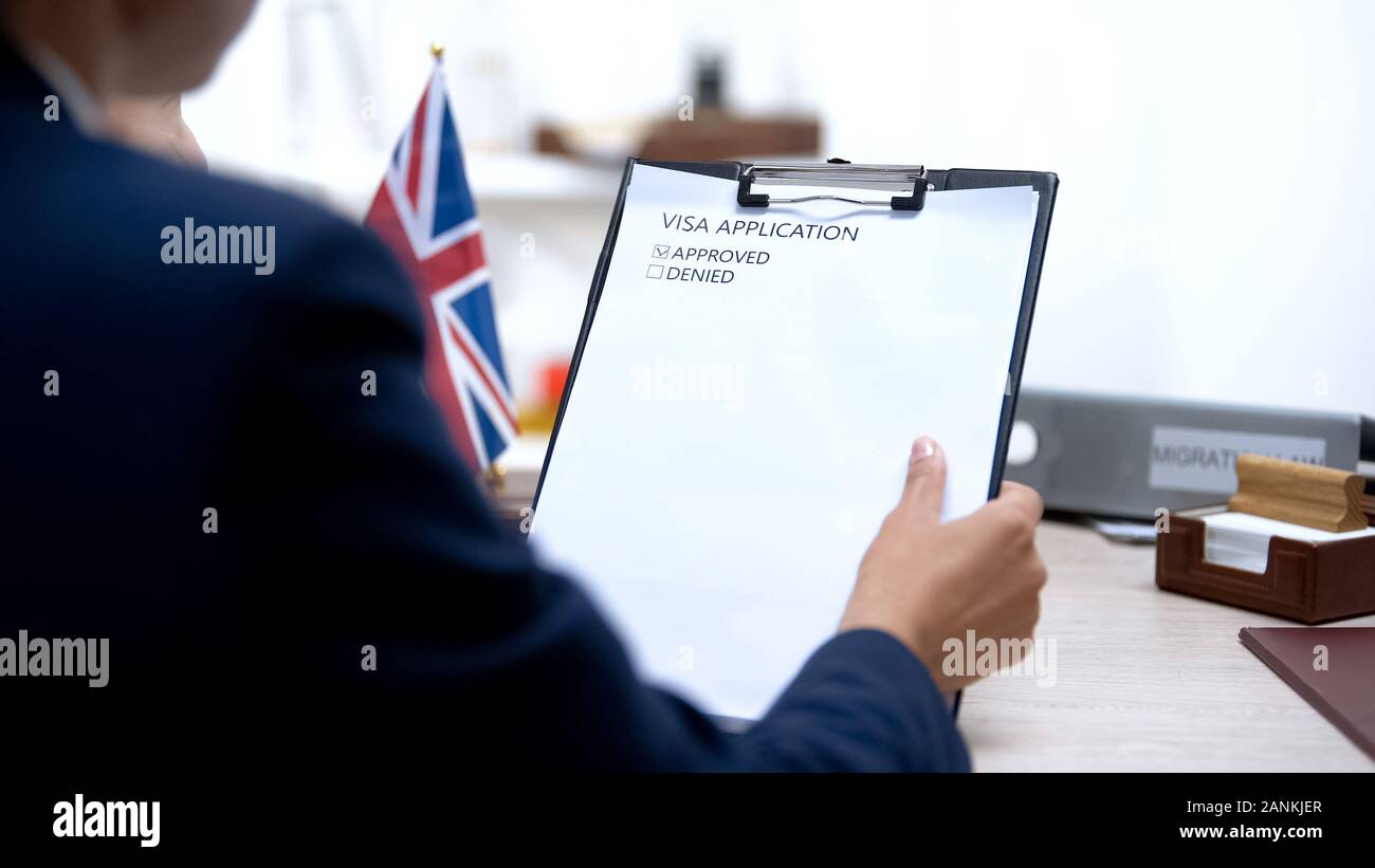 Consul looking at approved visa application, british flag on table ...