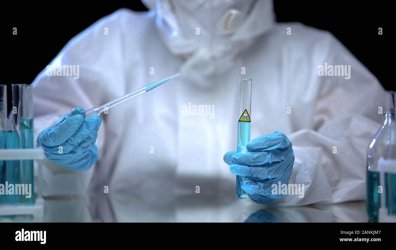 Person in protective suit taking sample with poison from test-tube, researches Stock Photo