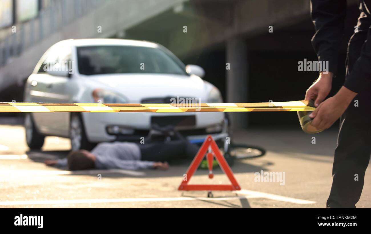 Policeman unrolling caution tape at traffic accident scene, warning