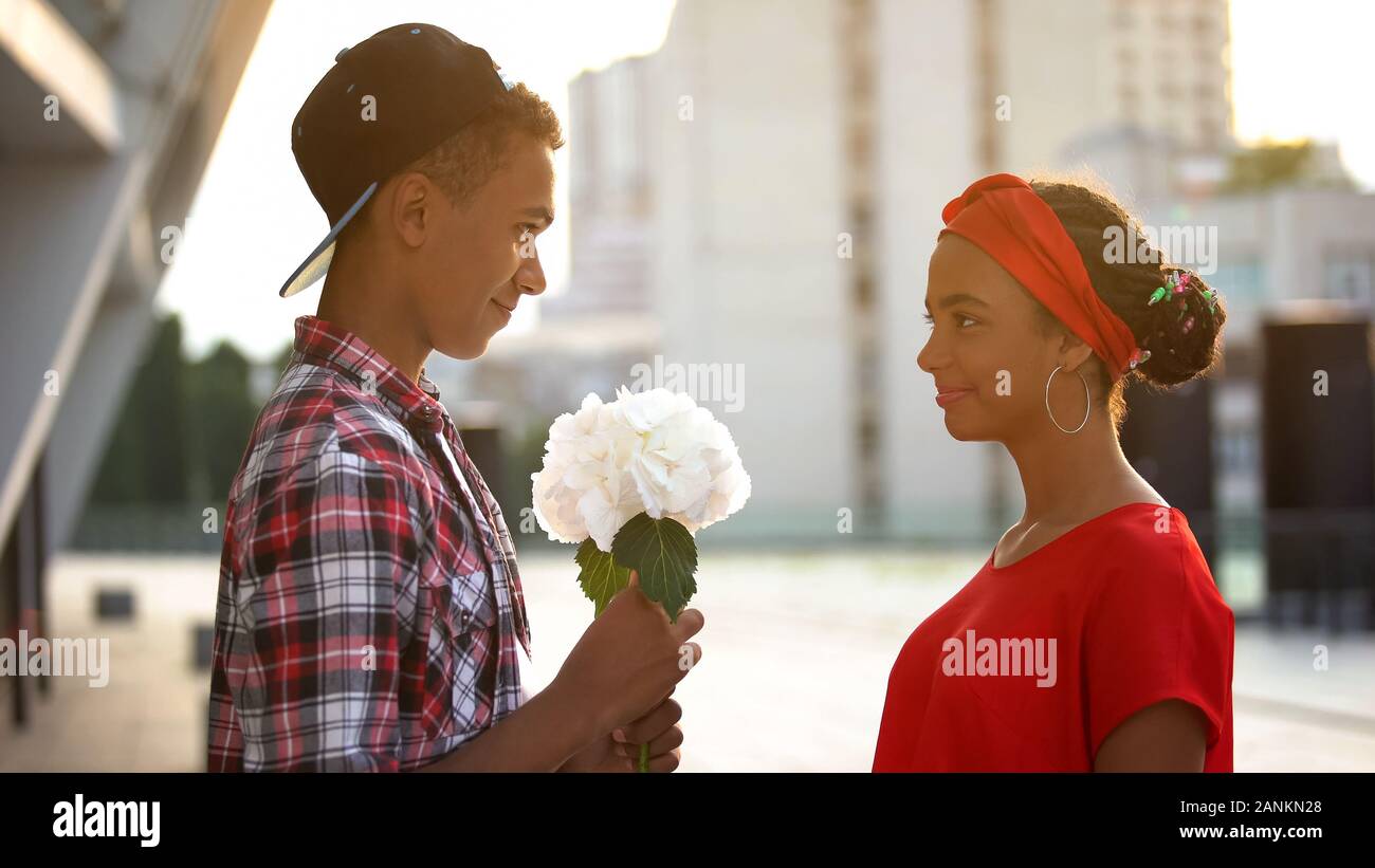 Teen boy giving flowers to beautiful girl, experiencing first love, romance  Stock Photo - Alamy
