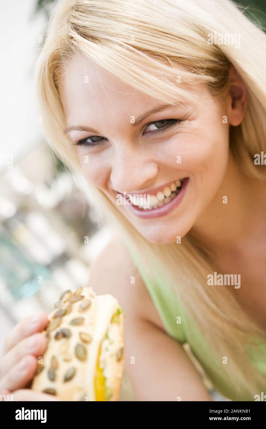 Fröhliche junge Frau hält ein Brötchen - Happy young woman holding bread roll Stock Photo