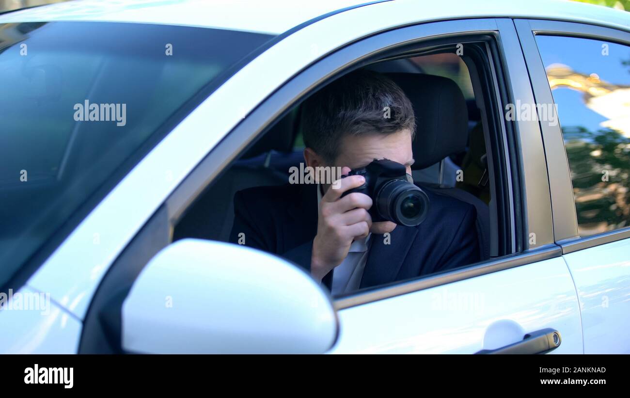 Private detective spying from car, taking photos on camera, investigation Stock Photo