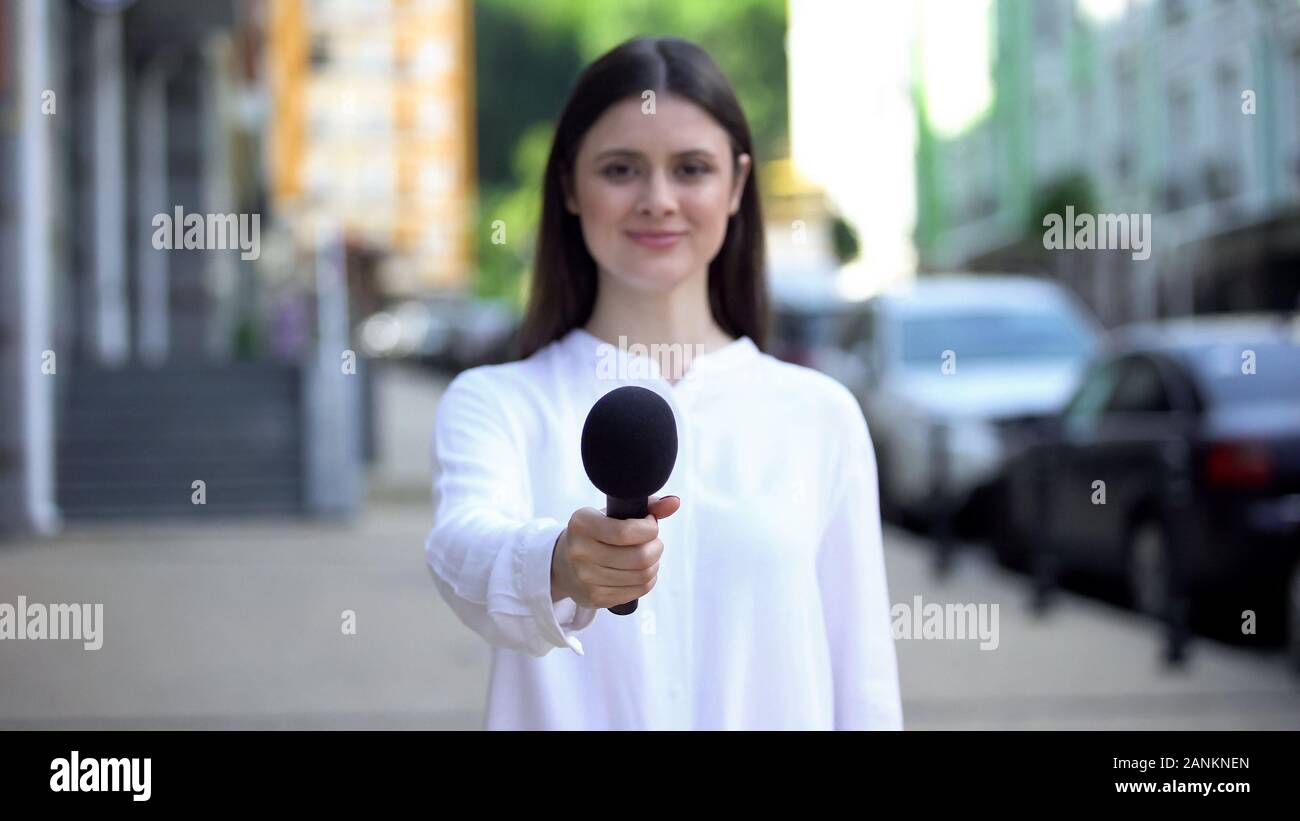 Female reporter proposing microphone, taking interview on street, daily news Stock Photo