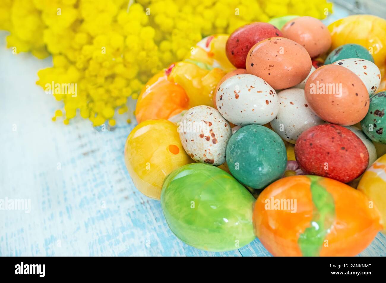 Easter eggs in ceramic form and Mimosa colors, on a wooden blue background. Easter Wallpaper. Copy space. Stock Photo