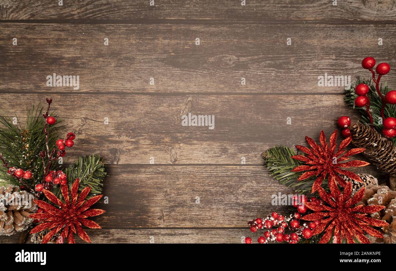 Christmas fir tree with red glitter poinsettie and berries on wooden background. Flatlay, top view, copy space. Stock Photo