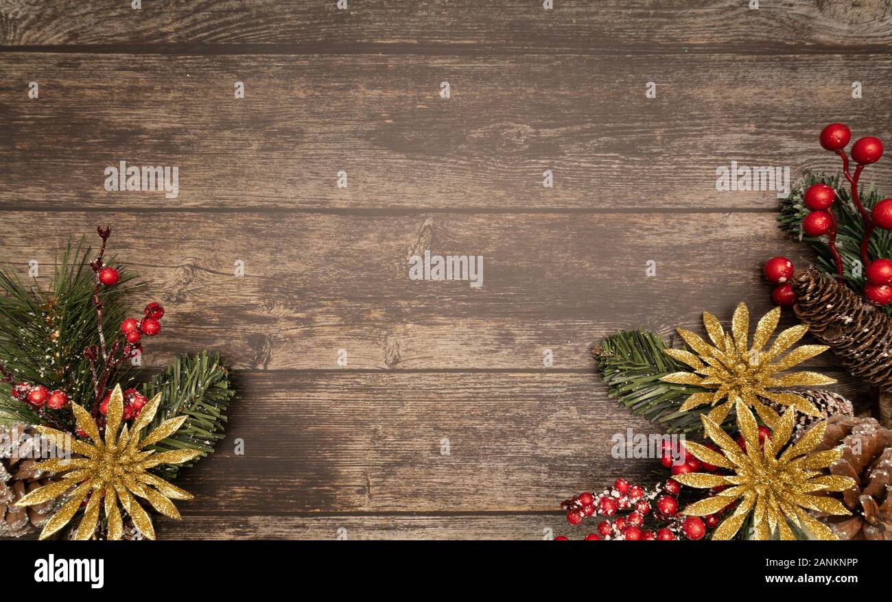 Christmas fir tree with gold glitter poinsettie and berries on wooden background. Flatlay, top view, copy space. Stock Photo