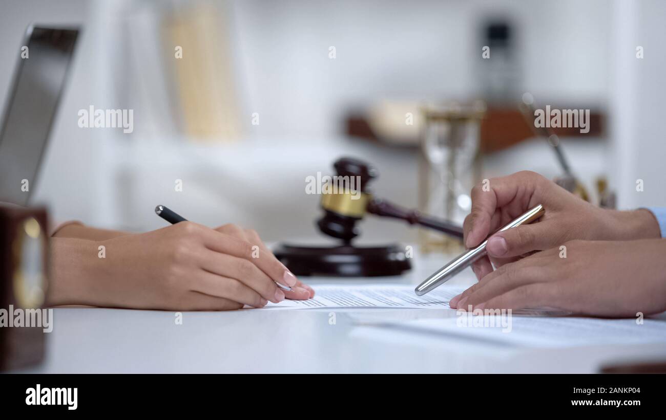 Lawyer showing woman where to sign court claim, professional help to plaintiff Stock Photo