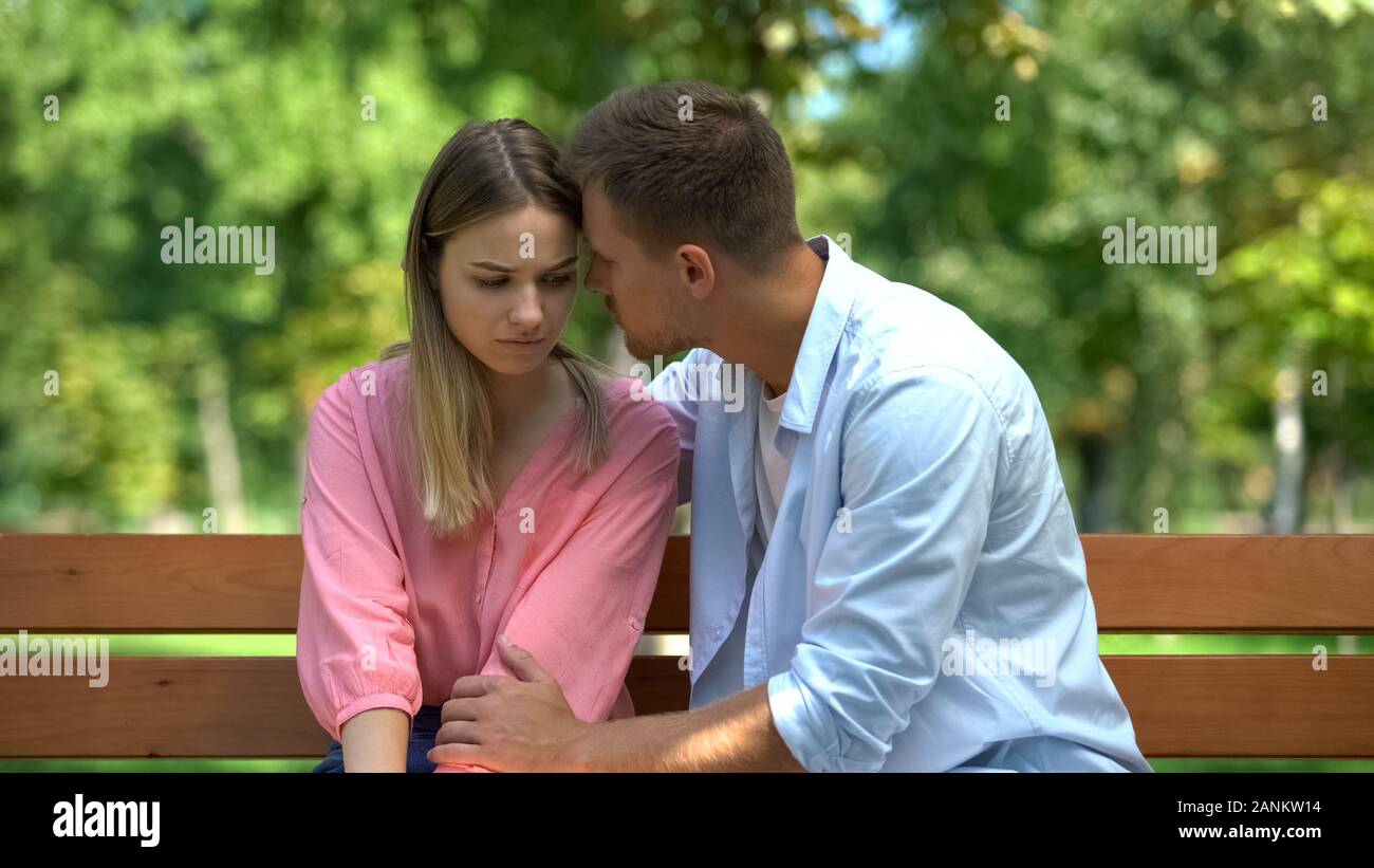 Young male supporting sad girlfriend sitting park bench together, loving spouse Stock Photo