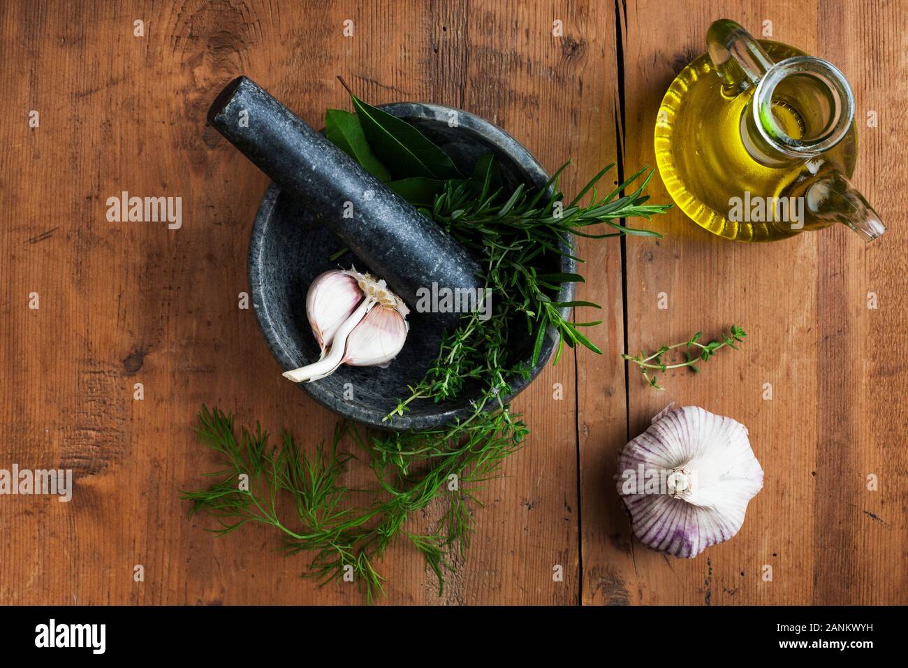 Mortar and pestle with garlic and herbs and olive oil Stock Photo