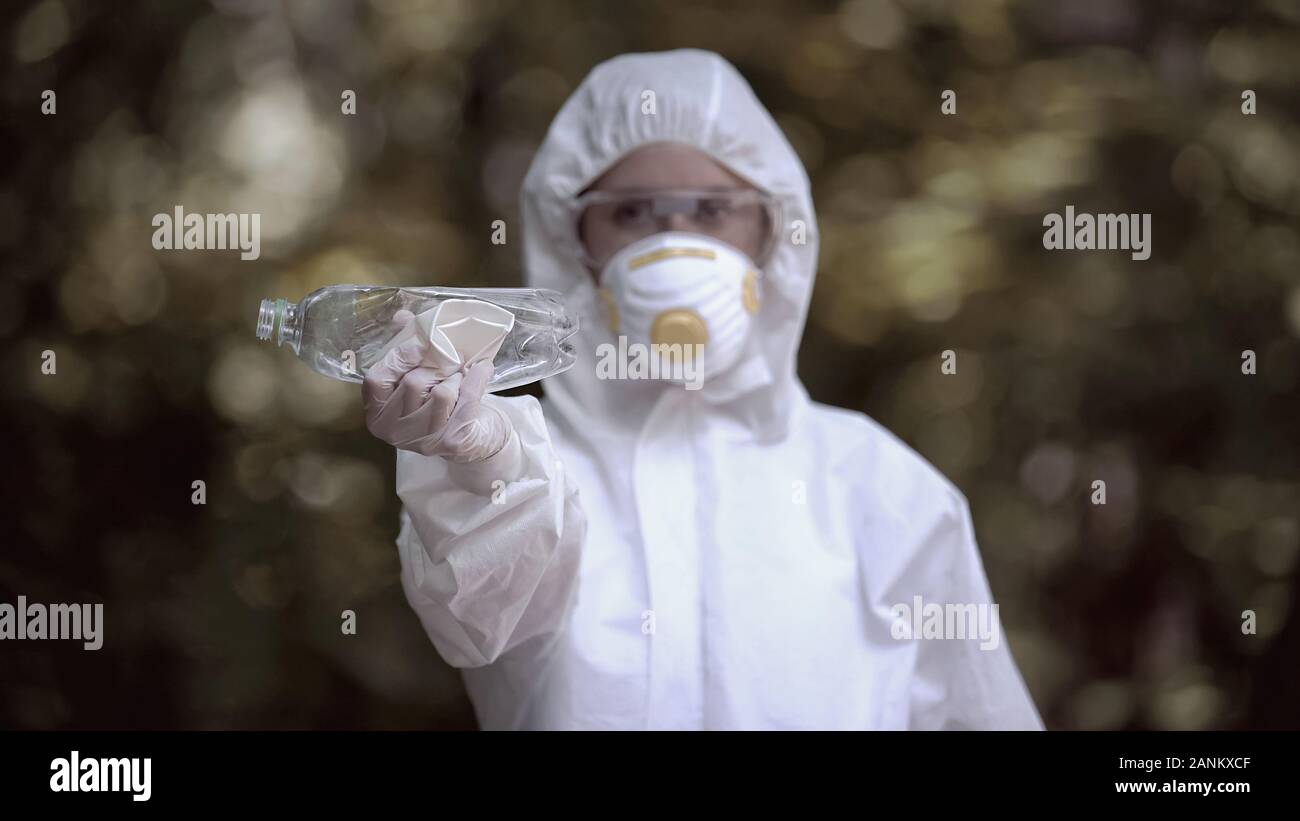 Biochemist holding crumpled plastic bottle and cup, abandoned dangerous place Stock Photo