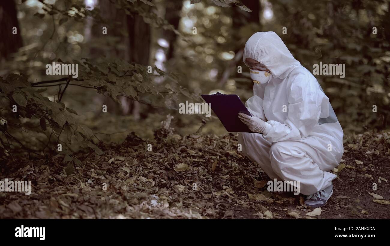 Female biologist analyzing forest leaves filling laboratory report, radiology Stock Photo