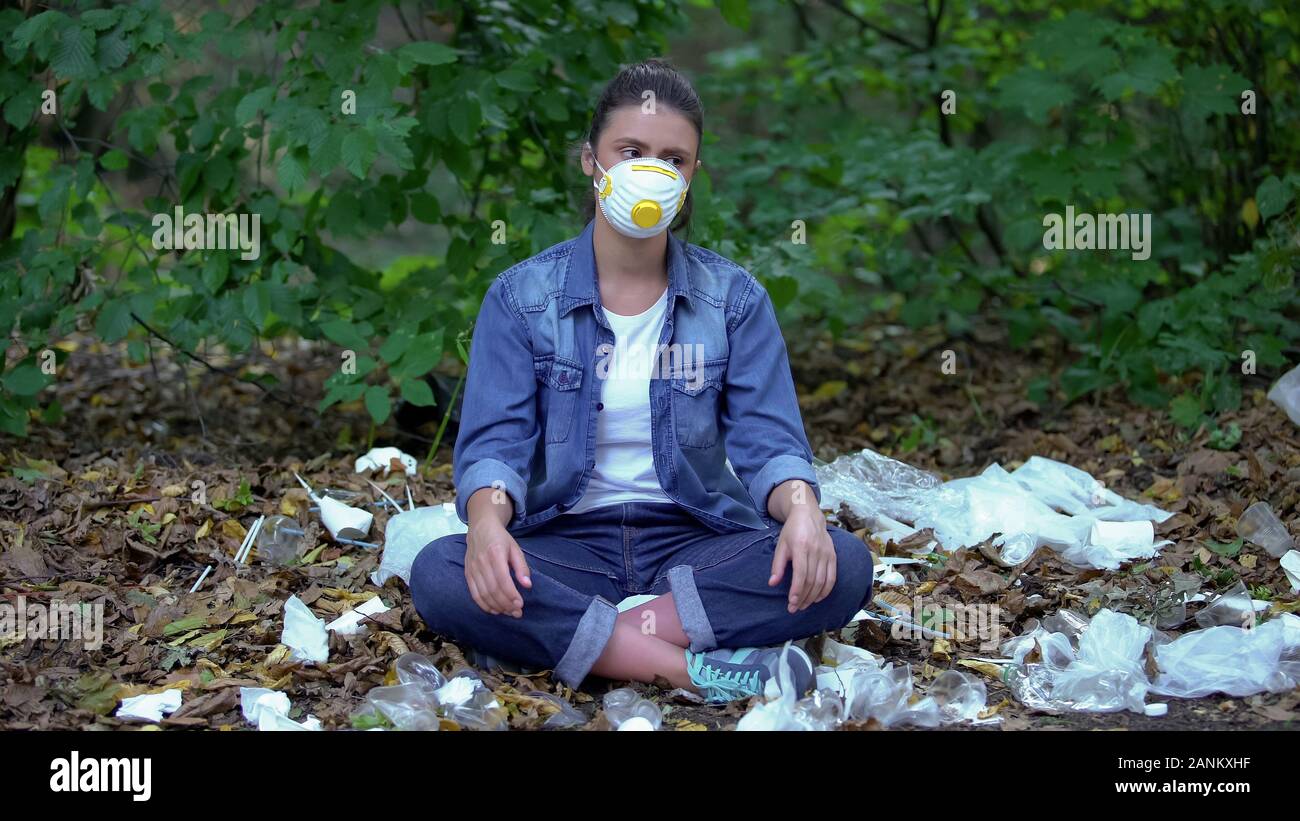 Female in protective mask sitting on plastic garbage in forest, toxic  future Stock Photo - Alamy