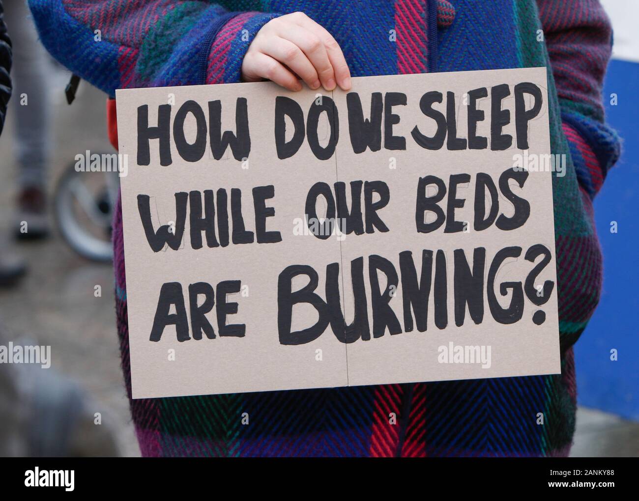 Mainz, Germany. 17th Jan, 2020. A protester holds a poster that reads “How  do we sleep while our beds are burning?”. Over 9,000 young people marched  through Mainz in a protest against