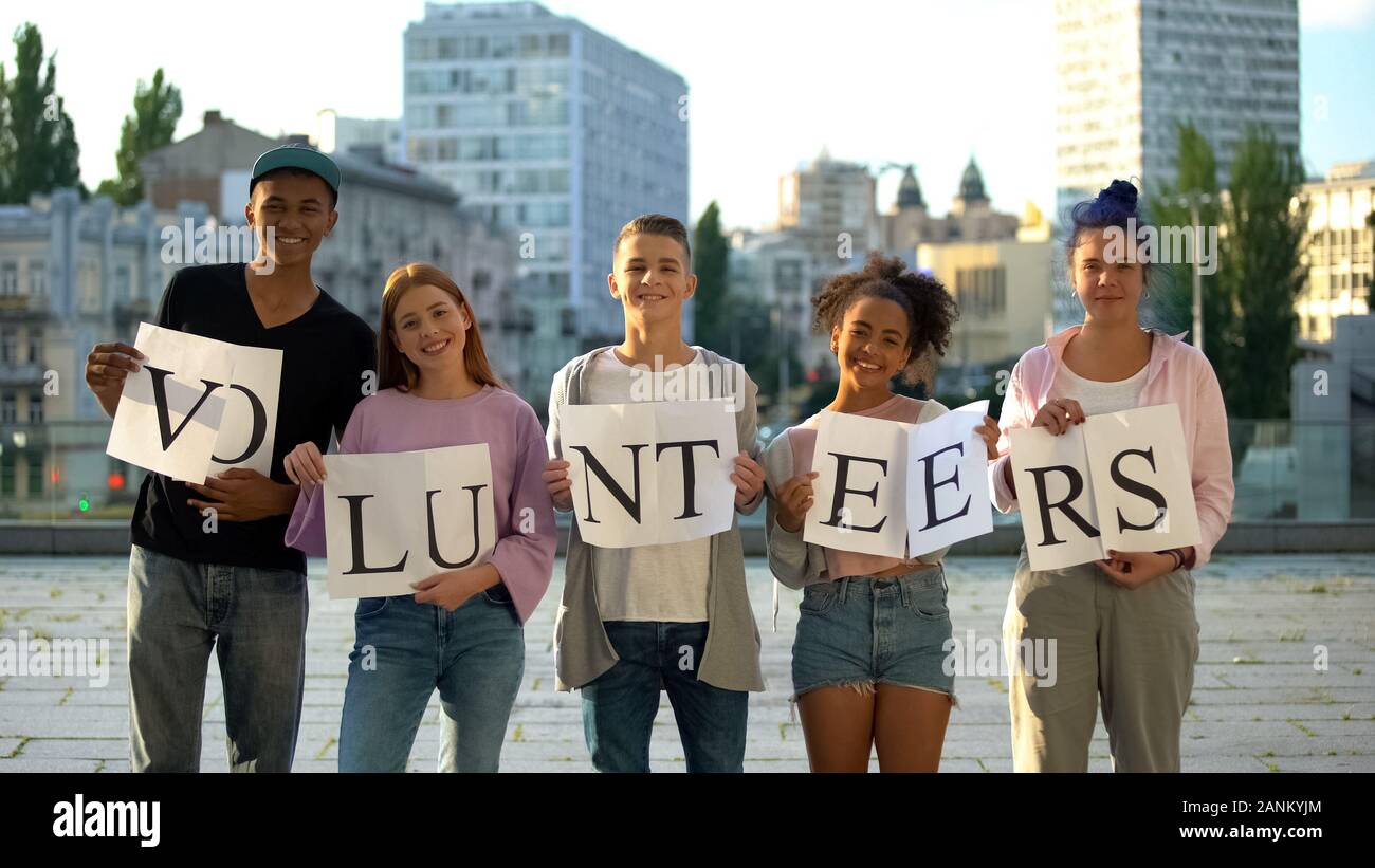 Happy group teenagers holding volunteers sign, social project, charity kindness Stock Photo