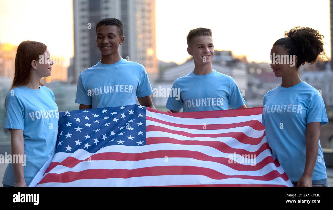 Joyful multiethnic volunteers holding American flag, charity project, support Stock Photo
