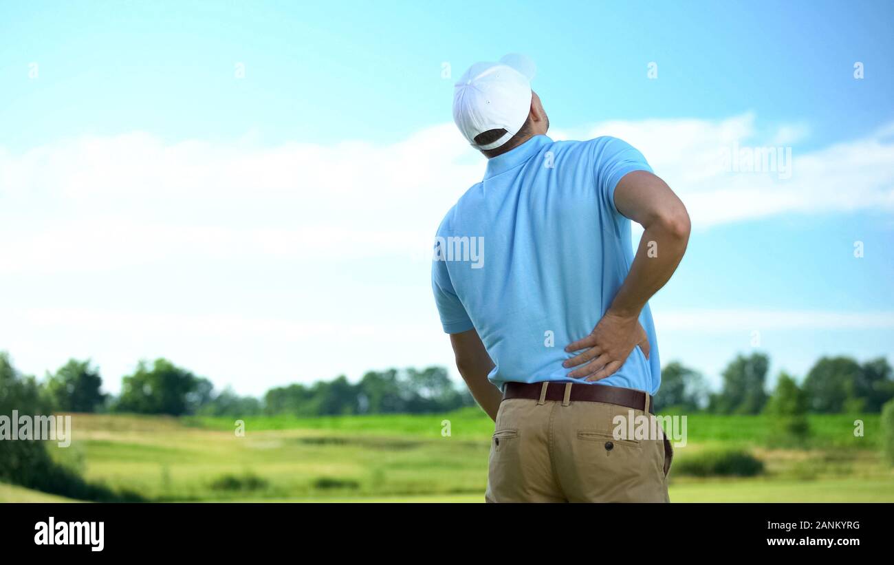 Athletic man golfer suffering sharp lower back pain, sport trauma, health Stock Photo