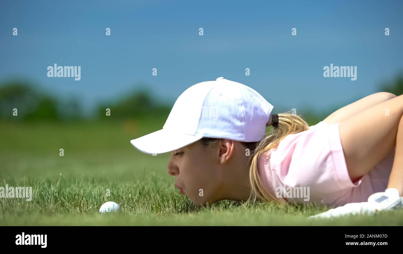 Funny female golf player blowing ball in hole, success strategy and cunning Stock Photo